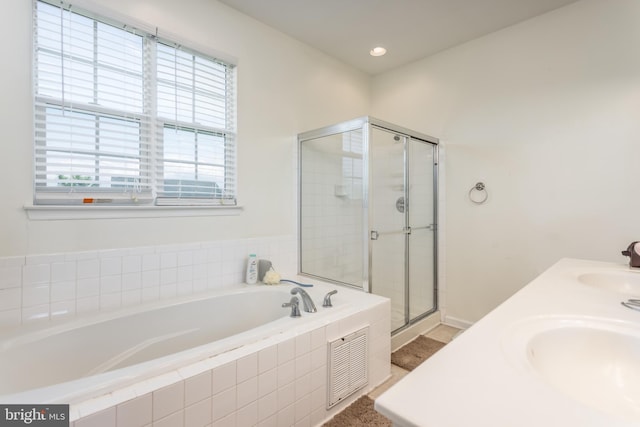 bathroom featuring a stall shower, a garden tub, and a sink