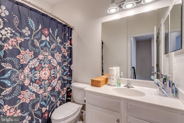 full bath with toilet, vanity, and curtained shower