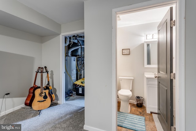 half bath with toilet, water heater, vanity, and baseboards