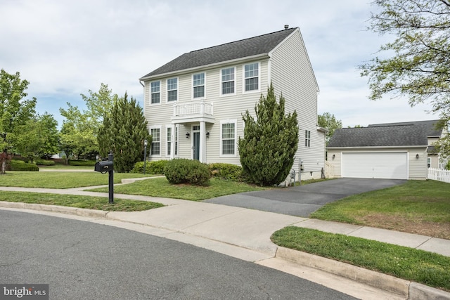 colonial-style house featuring a front lawn, a garage, an outdoor structure, and driveway