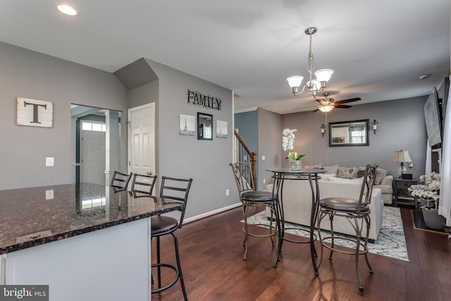 dining room featuring a ceiling fan, dark wood-style flooring, a chandelier, stairway, and baseboards