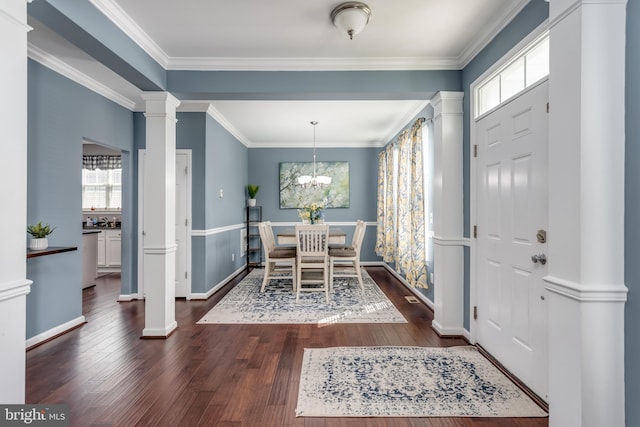 entrance foyer featuring decorative columns, healthy amount of natural light, dark wood-style floors, a chandelier, and crown molding