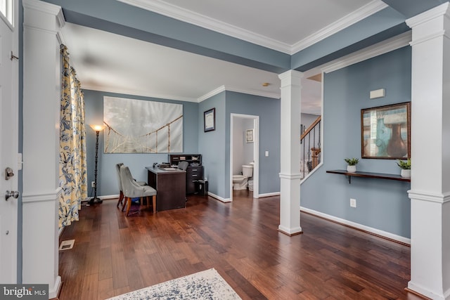 entryway with ornate columns, wood finished floors, crown molding, stairs, and baseboards
