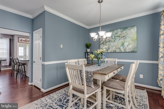 dining room with a chandelier, wood finished floors, crown molding, and baseboards