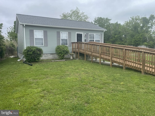 back of property with a lawn, a deck, and a shingled roof