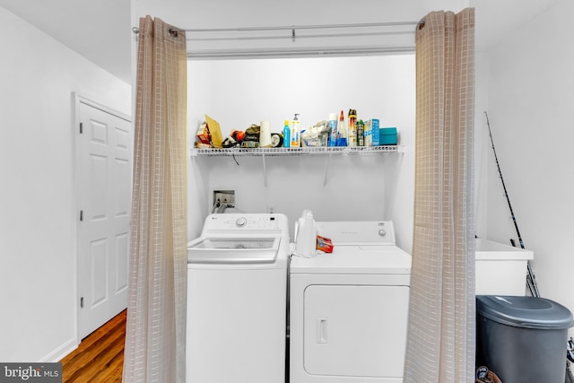 clothes washing area featuring separate washer and dryer and wood finished floors