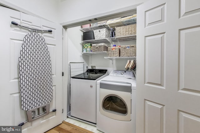clothes washing area featuring light wood finished floors, laundry area, and washer and clothes dryer