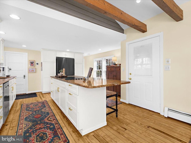 kitchen with fridge, a breakfast bar area, white cabinets, beamed ceiling, and light wood-type flooring
