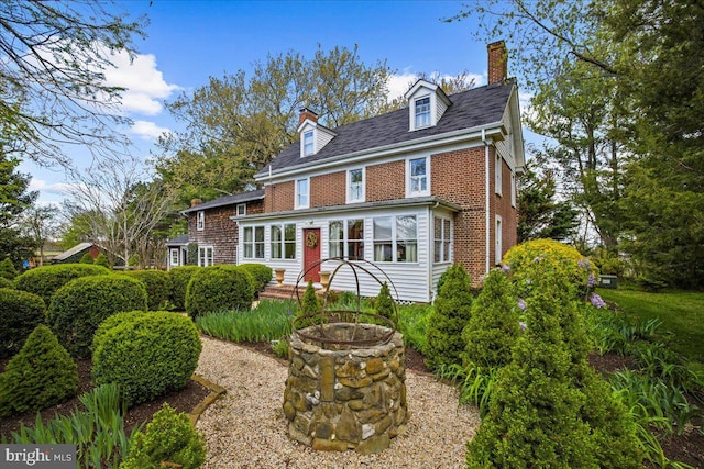rear view of house with a chimney, brick siding, and an outdoor fire pit