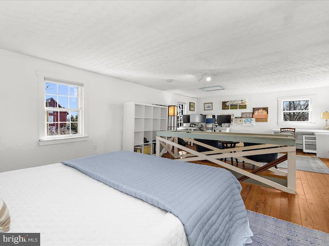 bedroom with wood-type flooring, an office area, and a textured ceiling