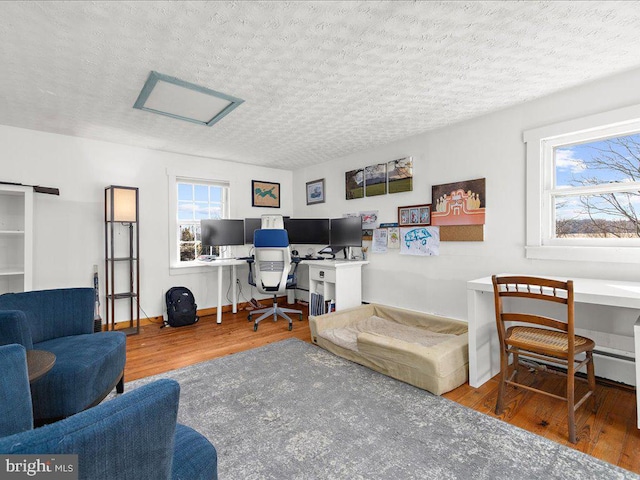 home office with wood finished floors, attic access, a textured ceiling, and baseboards