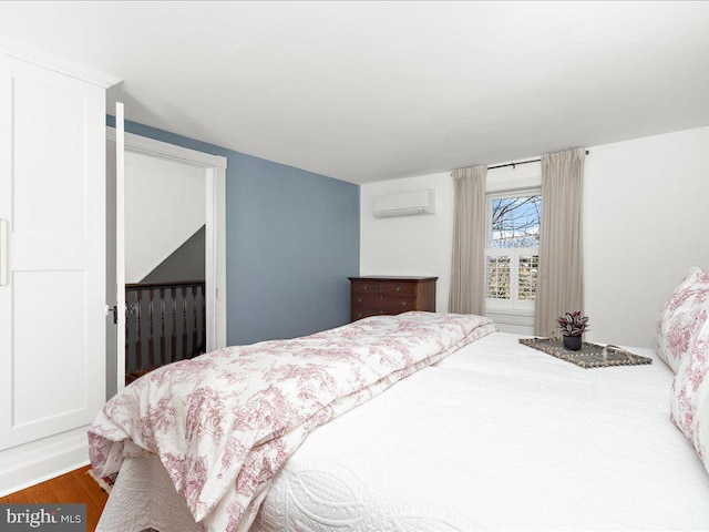 bedroom featuring a wall mounted air conditioner and wood finished floors
