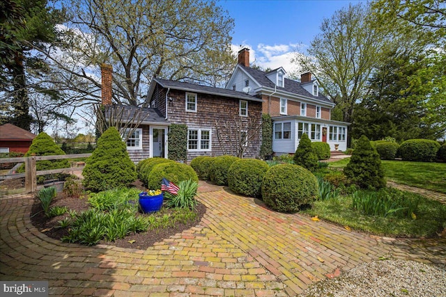 shingle-style home featuring a chimney and fence