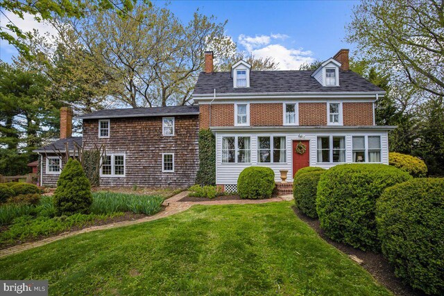 back of house featuring a chimney and a lawn