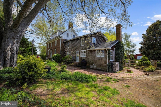 rear view of property with central air condition unit and fence