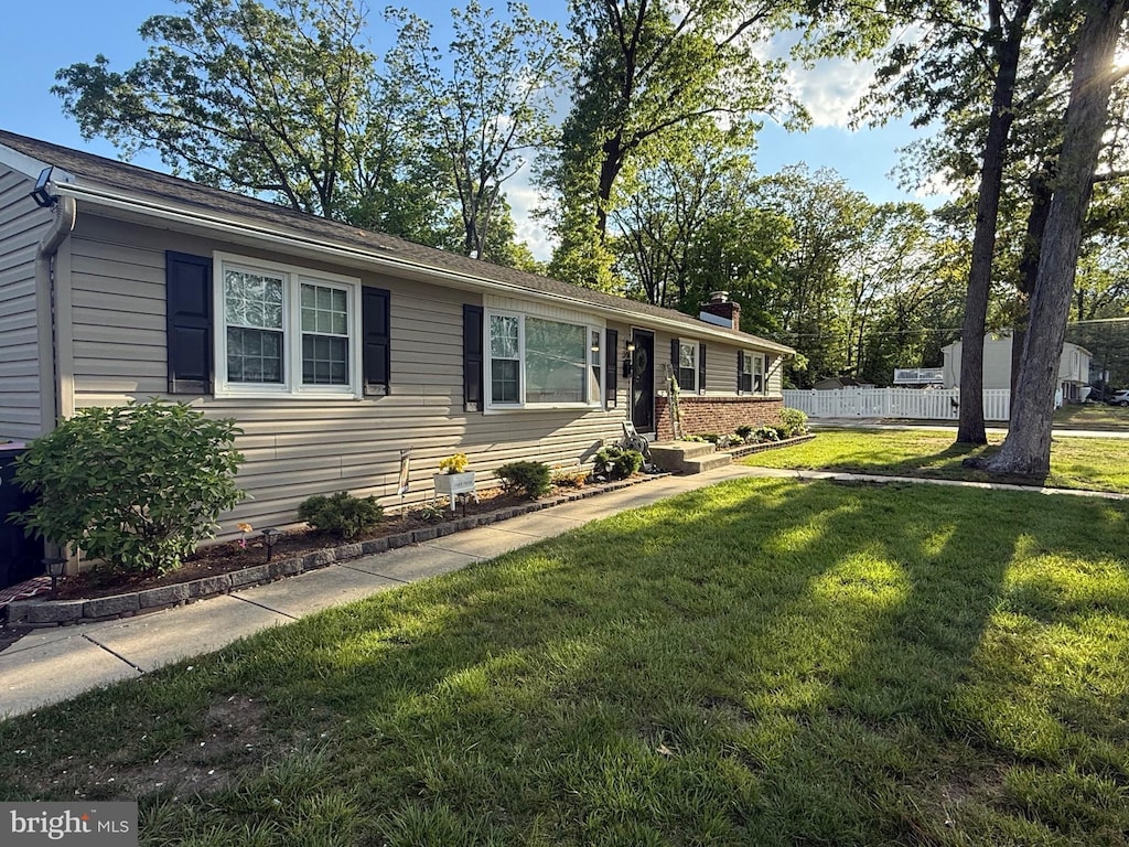 single story home featuring a chimney, a front yard, and fence