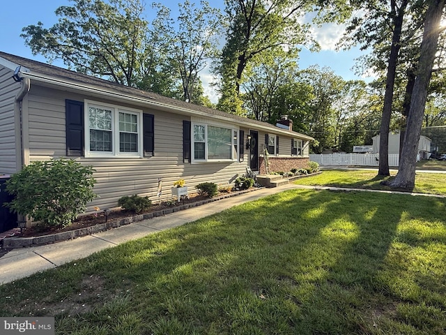 single story home featuring a chimney, a front yard, and fence