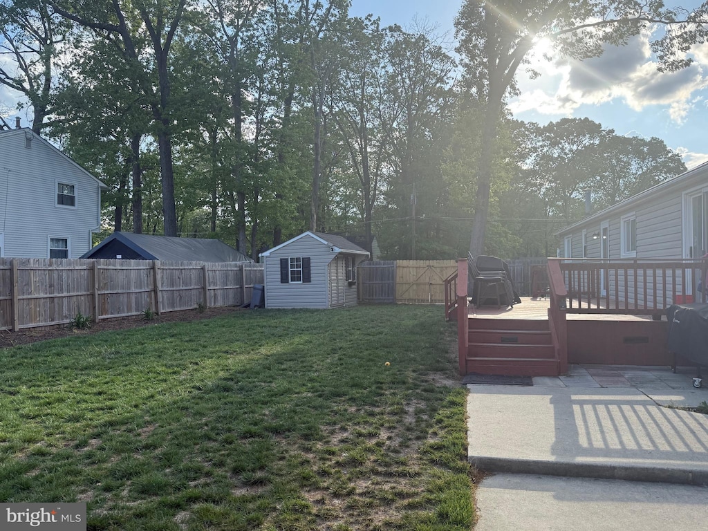 view of yard with a fenced backyard, a deck, a storage shed, and an outdoor structure