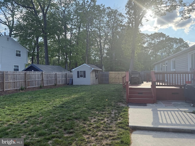 view of yard with a fenced backyard, a deck, a storage shed, and an outdoor structure