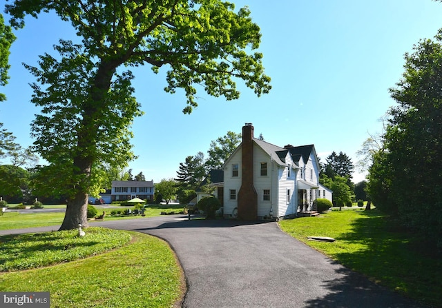 view of side of property with a yard and a chimney