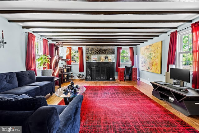 living area featuring wood finished floors, a fireplace, beam ceiling, and baseboards