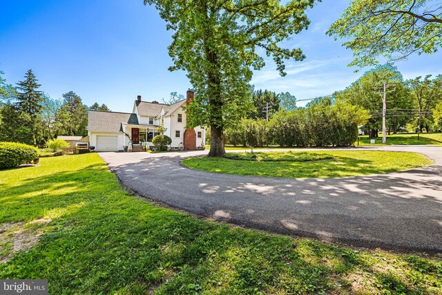 view of front of property with driveway, a front yard, a garage, and a chimney