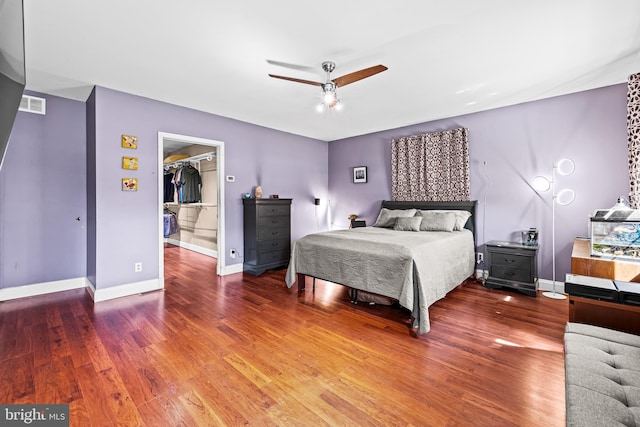 bedroom featuring wood finished floors, a spacious closet, baseboards, a ceiling fan, and a closet