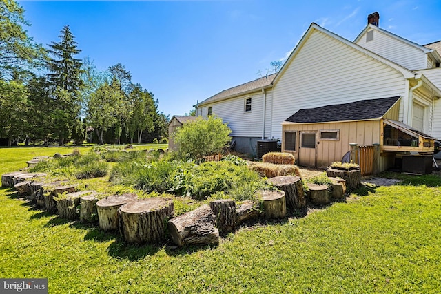 view of side of home featuring a lawn, a chimney, board and batten siding, cooling unit, and a shingled roof
