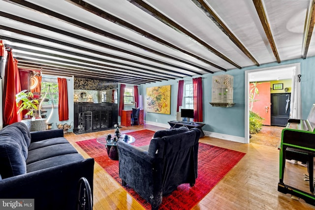 living room featuring beamed ceiling, baseboards, plenty of natural light, and wood finished floors