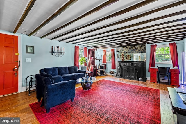 living room featuring wood finished floors, beam ceiling, and a fireplace with flush hearth
