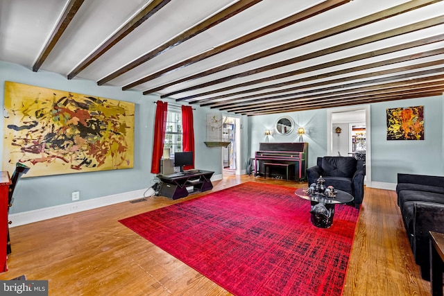 living area with beam ceiling, wood finished floors, baseboards, and a fireplace