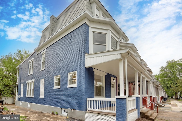 view of property exterior with brick siding and covered porch