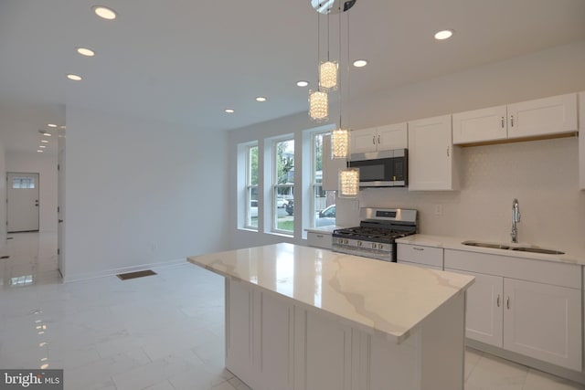 kitchen featuring stainless steel appliances, a sink, a kitchen island, recessed lighting, and white cabinetry