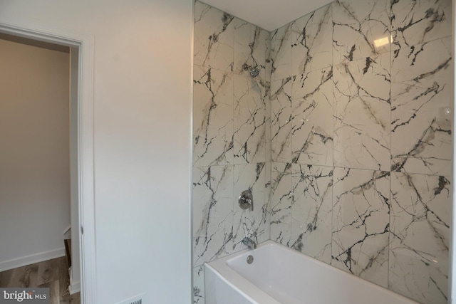 bathroom with shower / bath combination and wood finished floors