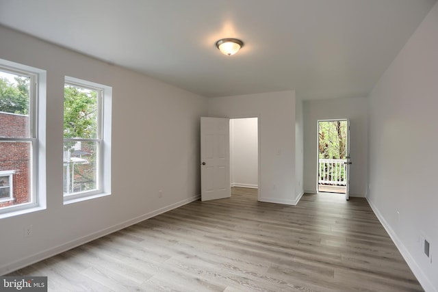unfurnished bedroom with multiple windows, light wood-style flooring, and baseboards