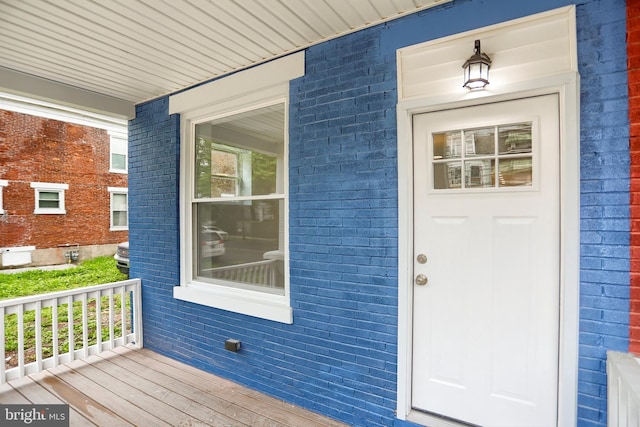 view of exterior entry with covered porch and brick siding