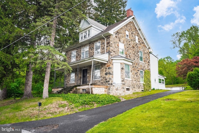 1050 Moravia St, Fountain Hill, PA 18015 - view of front facade featuring stone siding, covered porch, a chimney, and a front lawn