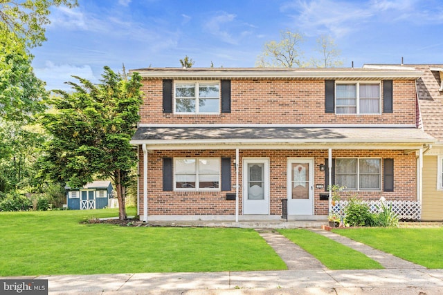 townhome / multi-family property featuring a front yard, brick siding, and an outdoor structure