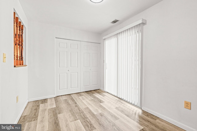 unfurnished bedroom with wood finished floors, baseboards, and a closet