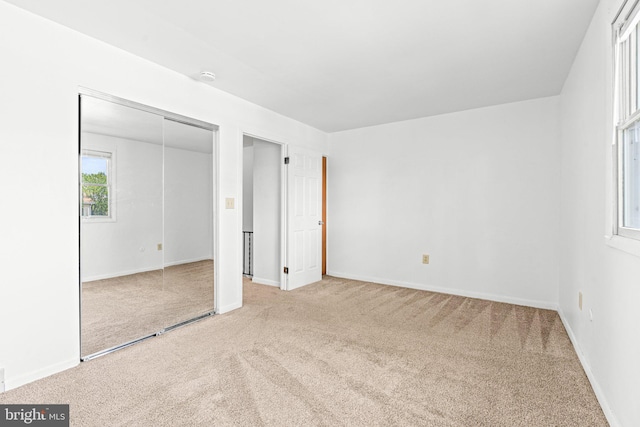 unfurnished bedroom featuring carpet, baseboards, and a closet
