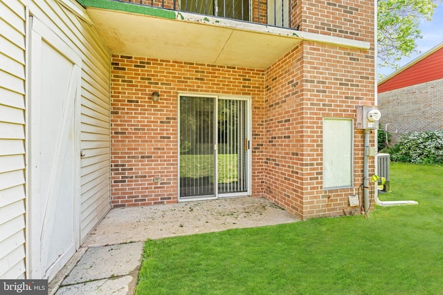 entrance to property with brick siding, a lawn, and cooling unit