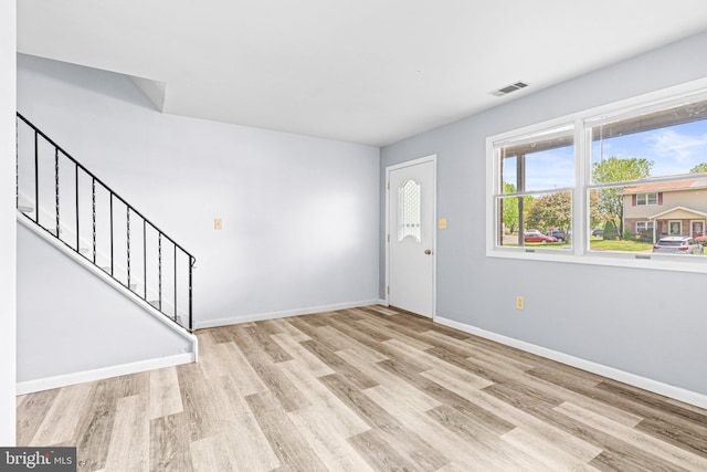 entryway with light wood-type flooring, stairs, and baseboards