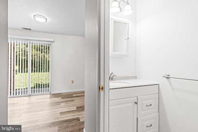 bathroom with wood finished floors, vanity, and baseboards