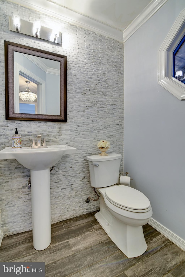 bathroom with crown molding, toilet, wood finished floors, and baseboards