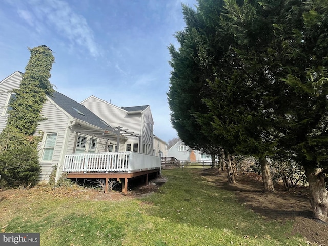 rear view of house with fence, a chimney, a deck, and a lawn