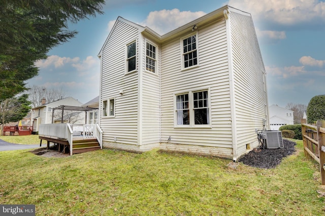 rear view of house with cooling unit, a lawn, and a wooden deck