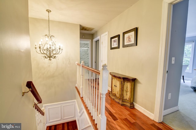 staircase featuring baseboards, a notable chandelier, and wood finished floors