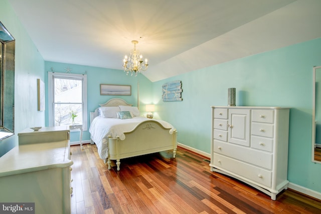 bedroom with lofted ceiling, a notable chandelier, baseboards, and wood finished floors