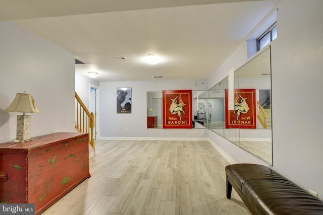 hallway featuring stairway, light wood-style flooring, and baseboards