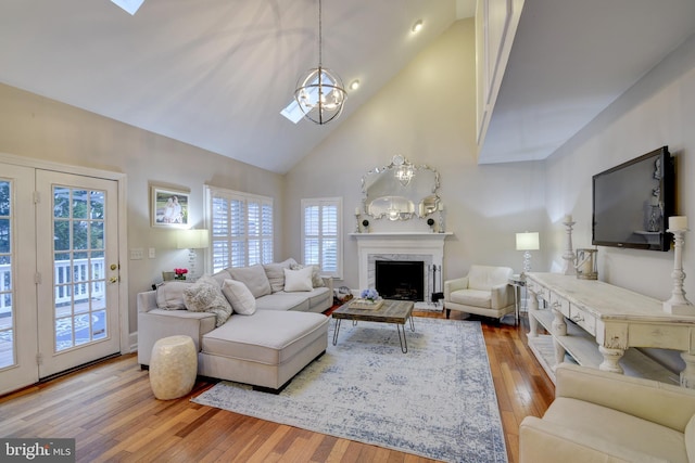 living area with an inviting chandelier, wood-type flooring, high vaulted ceiling, and plenty of natural light